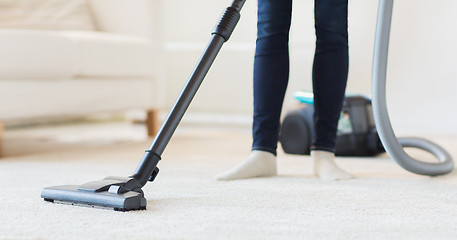 Image showing close up of woman legs with vacuum cleaner at home