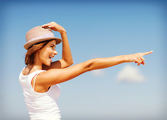 Image showing girl in hat showing direction on the beach