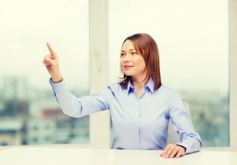 Image showing smiling woman pointing to something imaginary