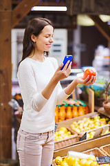 Image showing happy woman with smartphone and tomato in market