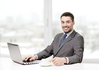 Image showing smiling businessman with laptop and coffee