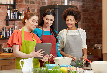 Image showing happy women with tablet pc cooking in kitchen