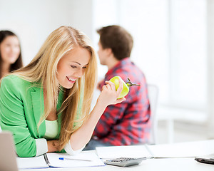 Image showing smiling student girl eating apple at school