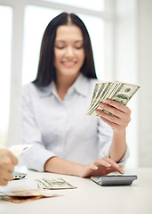 Image showing close up of woman counting money with calculator