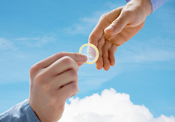 Image showing close up of male gay couple hands giving condom