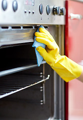 Image showing close up of woman cleaning oven at home kitchen