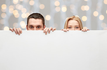 Image showing happy couple hiding behind big white blank board