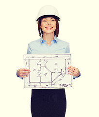 Image showing smiling businesswoman in helmet showing blueprint