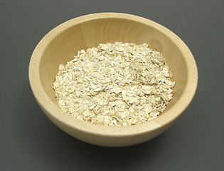 Image showing Wooden bowl with oat flakes on a dull matting