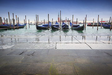 Image showing Gondolas moored in front of pavement