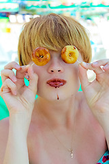 Image showing Playful girl holding donuts on her eyes. 