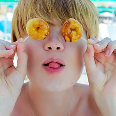 Image showing Playful girl holding donuts on her eyes. 