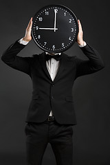 Image showing Handsome young man holding a clock