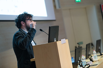 Image showing Speaker giving talk on podium at Business Conference.