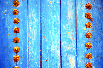 Image showing dirty stripped paint in the blue wood door and rusty 
