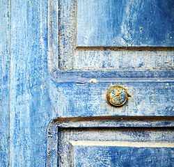 Image showing stripped paint in the blue wood door and rusty nail