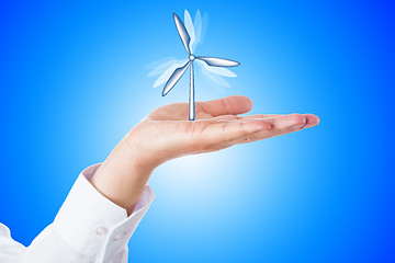 Image showing Wind Turbine Turning In A Palm On Blue Background