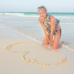 Image showing Woman drawing heart on the sand.