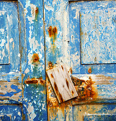 Image showing dirty stripped paint in the blue wood door and rusty nail