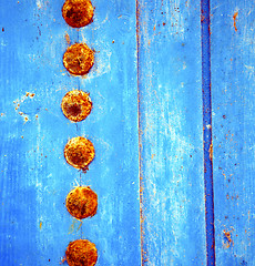 Image showing dirty stripped paint in the blue wood door and rusty nail