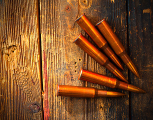 Image showing five rifle cartridges on wooden surface