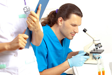 Image showing scientist looking through a microscope