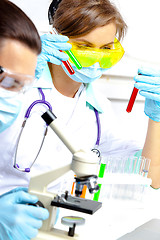 Image showing doctor in a mask examines test tubes