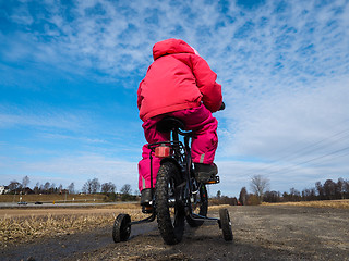 Image showing Little girl biker on gravle road with supporting wheels on grave