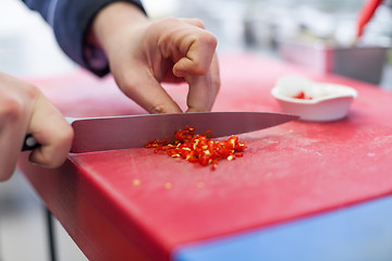 Image showing Chef dicing red hot chili peppers