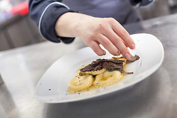 Image showing Chef grating truffle mushroom onto ravioli pasta