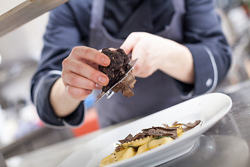 Image showing Chef grating truffle mushroom onto ravioli pasta