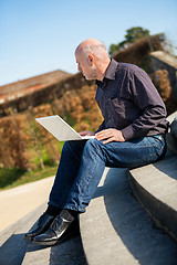 Image showing Man sitting on a bench using a laptop