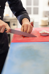 Image showing Chef dicing red hot chili peppers