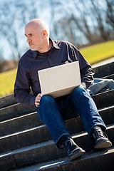 Image showing Man sitting on a bench using a laptop