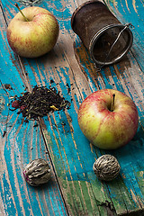 Image showing tea leaves and red apple on wooden background