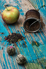 Image showing tea leaves and red apple on wooden background