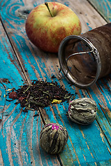 Image showing tea leaves and red apple on wooden background