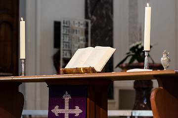 Image showing Open Bible and candles on the altar of a church