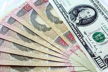 Image showing 100 dollars and grivnas banknotes isolated on dark background