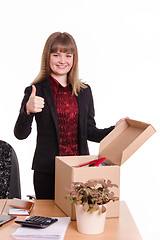Image showing The girl behind the office desk with a box showing thumb