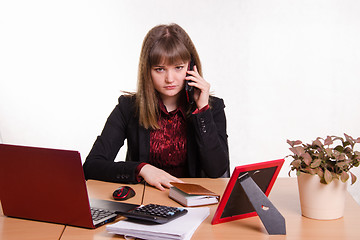 Image showing The girl behind office table talks on phone