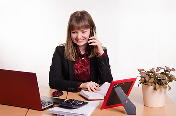 Image showing The girl behind office desk talking on phone