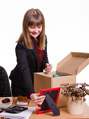 Image showing Girl puts a photo frame on desktop in office