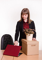 Image showing Dismissed girl in office with a box and flower closes laptop