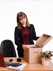 Image showing Dismissed girl in office near table collects personal belongings a box