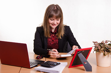 Image showing Joyful Girl sitting office desk, looking at notebook