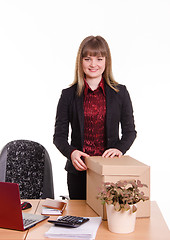 Image showing Smiling girl at office desk with a big box