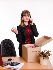 Image showing Girl in office collects personal belongings and calling on phone