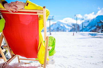 Image showing Women at mountains in winter lies on sun-lounger