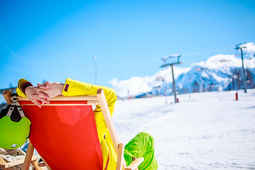 Image showing Women at mountains in winter lies on sun-lounger